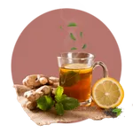 Image of Ceylon tea in a glass cup surrounding ginger and lime on a wooden table top.